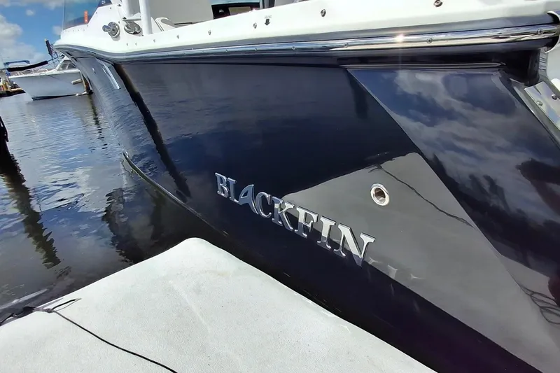 Yacht Photos Pics 2023 Blackfin 272DC boat docked, showcasing sleek design and reflective hull.