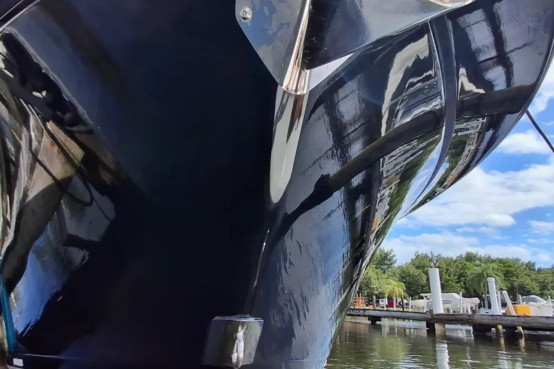  Yacht Photos Pics 2023 Blackfin 272DC boat hull reflecting water and sky at a marina.