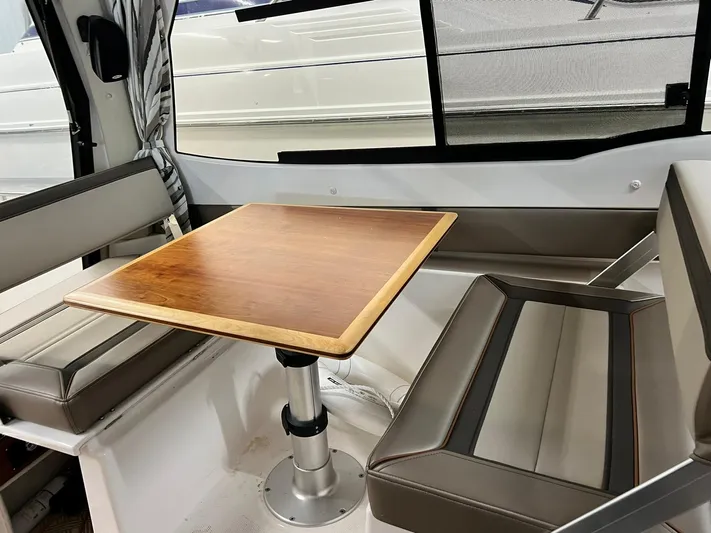  Yacht Photos Pics Interior of 2022 Cutwater C-24 Coupe with wooden table and cushioned seating.