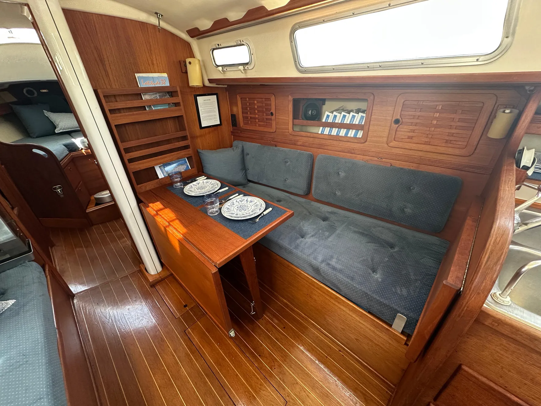 1985 Sabre 34 MKI yacht interior with wooden dining area and blue cushioned seating.