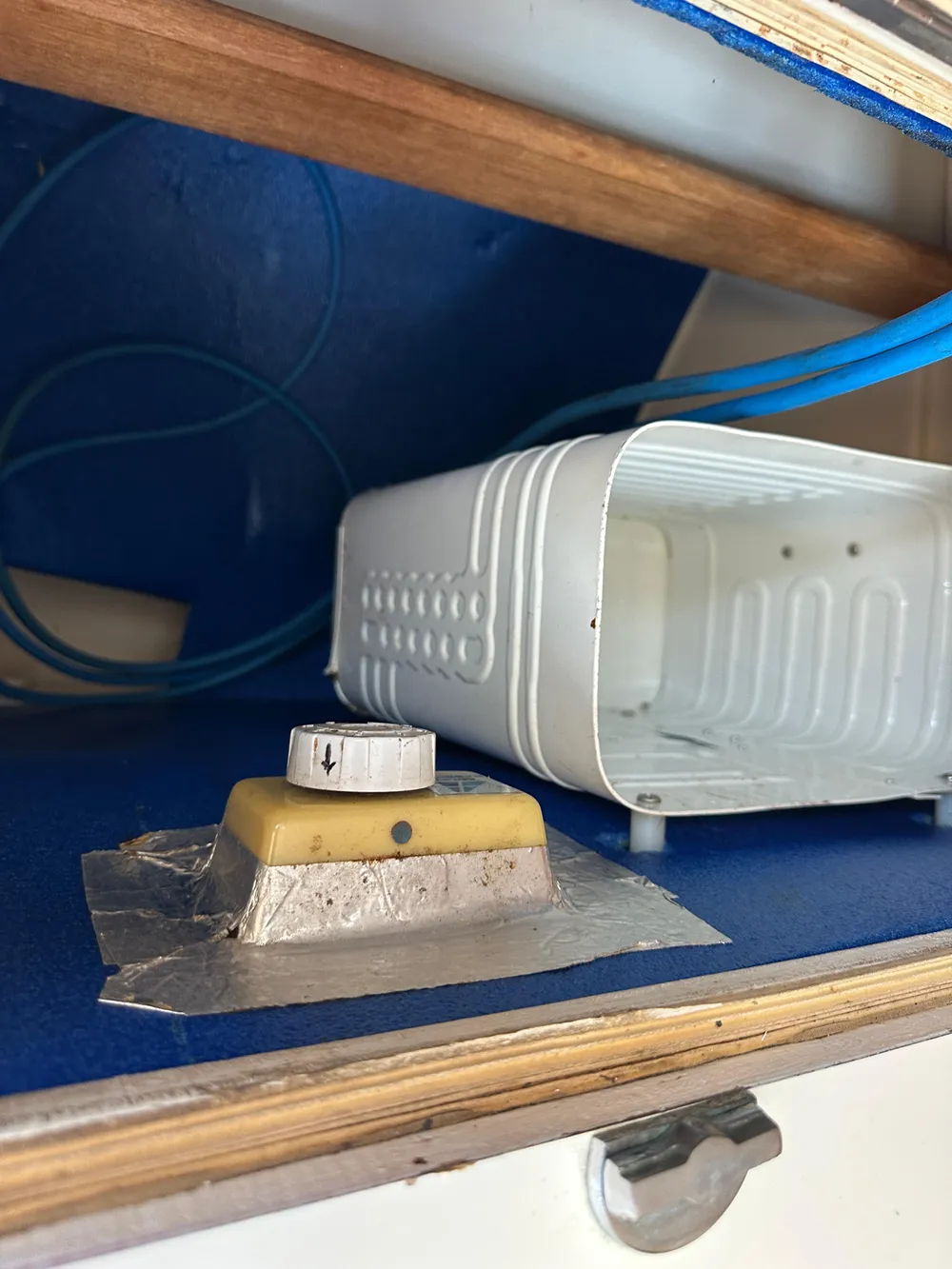 Interior detail of a 1985 Sabre 34 MKI sailboat, featuring a storage area with a knob and container.