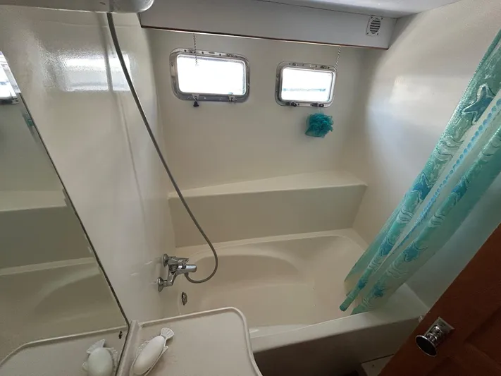 Duet Yacht Photos Pics Bathroom with shower and tub in 1999 Selene 43 yacht, featuring porthole windows and blue shower curtain.