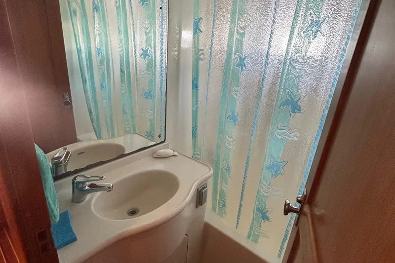 Duet Yacht Photos Pics Compact bathroom with a white sink and starfish-patterned shower curtain in a 1999 Selene 43.