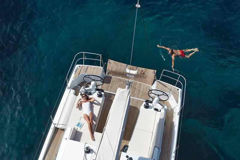 Yacht Photos Pics Manufacturer Provided Image: 2020 Jeanneau Sun Odyssey 490 yacht with people relaxing and swimming in clear blue water.