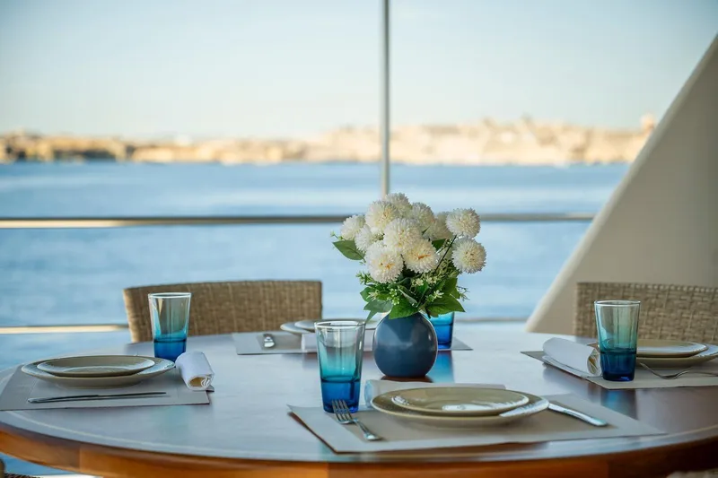 Voyager Yacht Photos Pics Elegant yacht dining setup with flowers, overlooking serene ocean view.