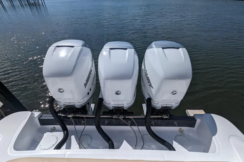 'why Knot' Yacht Photos Pics Triple Mercury outboard engines on a 2008 Donzi 38 ZSF boat, docked on calm water.