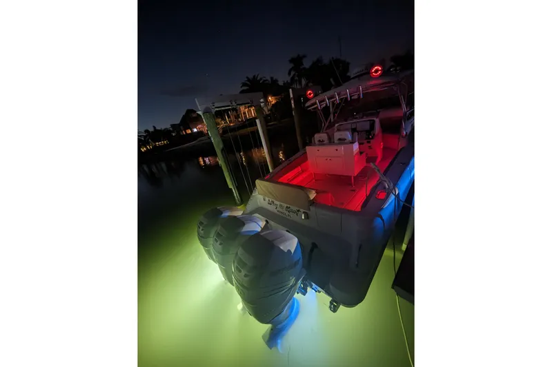 'why Knot' Yacht Photos Pics 2008 Donzi 38 ZSF boat illuminated at night with vibrant underwater lights.