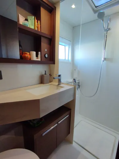Alma De Sur Yacht Photos Pics Modern bathroom in 2021 Lagoon 46 yacht with shower, sink, and storage shelves.