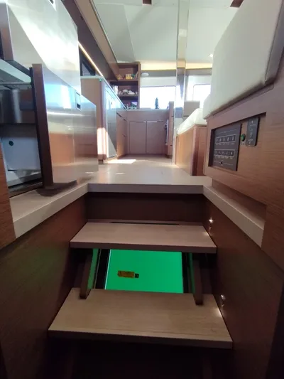 Alma De Sur Yacht Photos Pics Interior view of 2021 Lagoon 46 catamaran, featuring modern kitchen and wooden stairs.