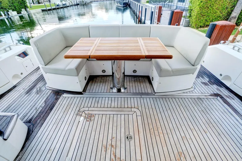Joie De Vivre Yacht Photos Pics Luxury seating area on 2020 Sunseeker Manhattan 52 yacht with wooden table and waterfront view.