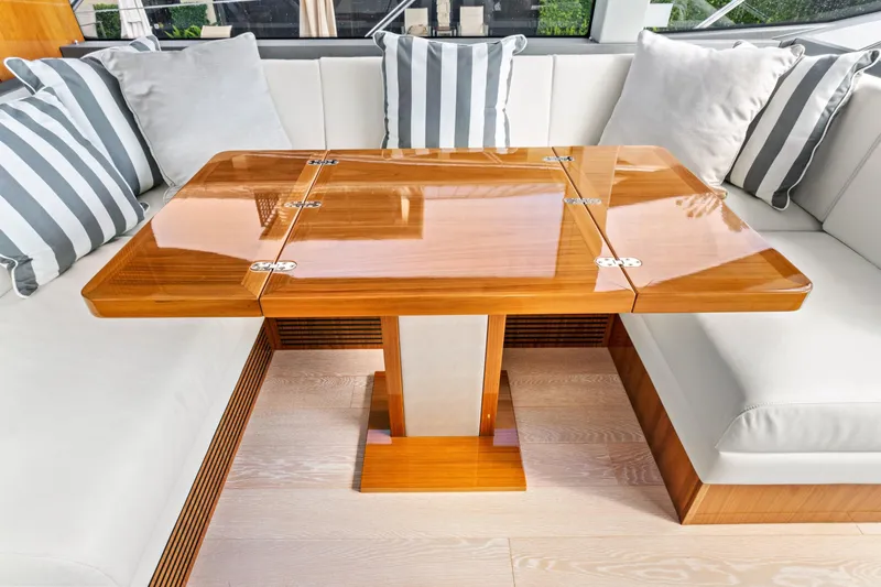 Joie De Vivre Yacht Photos Pics Luxurious interior of 2020 Sunseeker Manhattan 52 yacht with elegant wooden table and striped cushions.