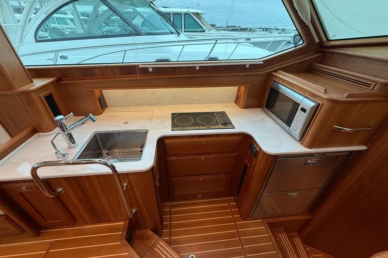 Kay Lee Jean Yacht Photos Pics 2023 Sabre 43 Salon Express yacht kitchen with wood cabinetry, sink, stove, and microwave.
