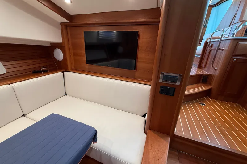 Kay Lee Jean Yacht Photos Pics 2023 Sabre 43 Salon Express interior with white seating, wood paneling, and a mounted TV.