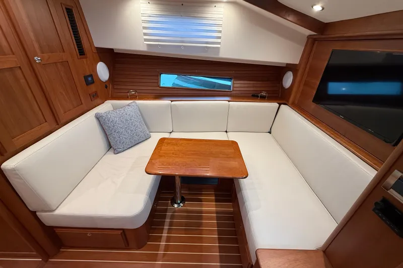 Kay Lee Jean Yacht Photos Pics 2023 Sabre 43 Salon Express interior with cozy seating and wooden table.