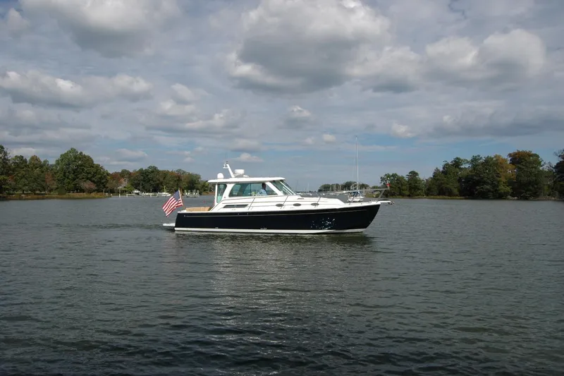 Au Lapin Agile Yacht Photos Pics 2014 Back Cove 34 boat cruising on a calm lake under a cloudy sky.