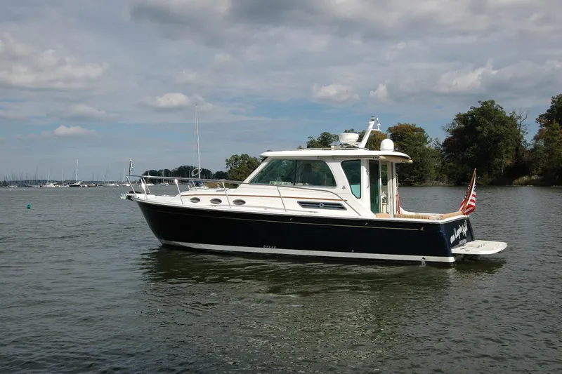 Au Lapin Agile Yacht Photos Pics 2014 Back Cove 34 boat on calm water, with trees and cloudy sky in background.