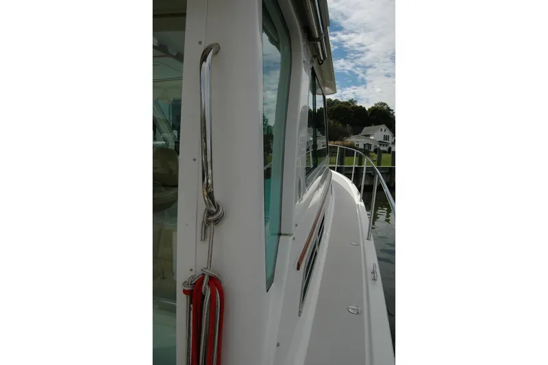 Au Lapin Agile Yacht Photos Pics 2014 Back Cove 34 boat side view with railing and docked houses in background.