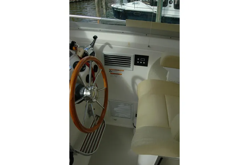 Au Lapin Agile Yacht Photos Pics 2014 Back Cove 34 boat helm with wooden steering wheel and beige seating.