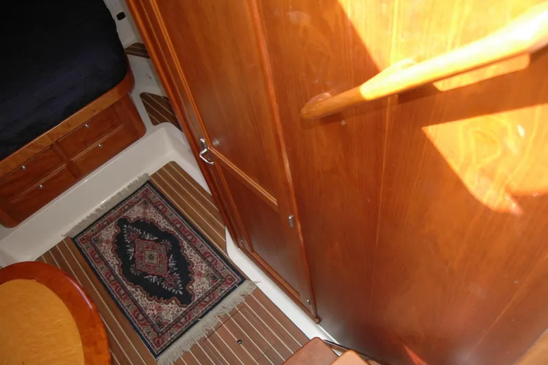 Au Lapin Agile Yacht Photos Pics 2014 Back Cove 34 interior with wooden cabinetry, striped rug, and cozy sleeping area.