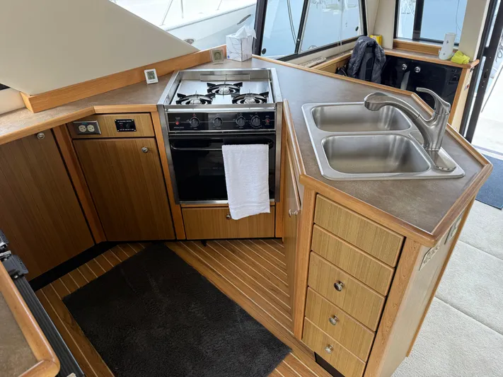  Yacht Photos Pics 2001 Bayliner 3988 Command Bridge Motoryacht kitchen with stove, sink, and wooden cabinetry.