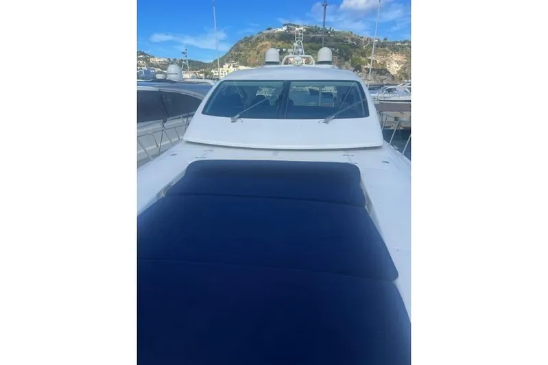  Yacht Photos Pics 2009 Overmarine Mangusta 72 HT yacht with blue sunbed, docked in a scenic marina.