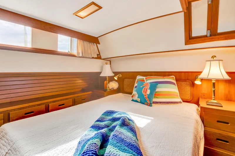 Lu-sea-lu Yacht Photos Pics Cozy bedroom in 1994 Grand Banks 42 Classic yacht with colorful pillows and wooden accents.