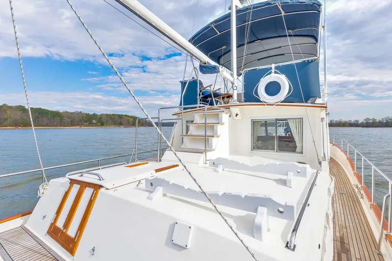 Lu-sea-lu Yacht Photos Pics Grand Banks 42 Classic yacht, 1994 model, cruising on a serene lake under a partly cloudy sky.