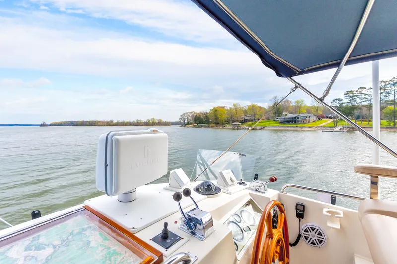 Lu-sea-lu Yacht Photos Pics Helm of 1994 Grand Banks 42 Classic yacht overlooking serene lake and shoreline.