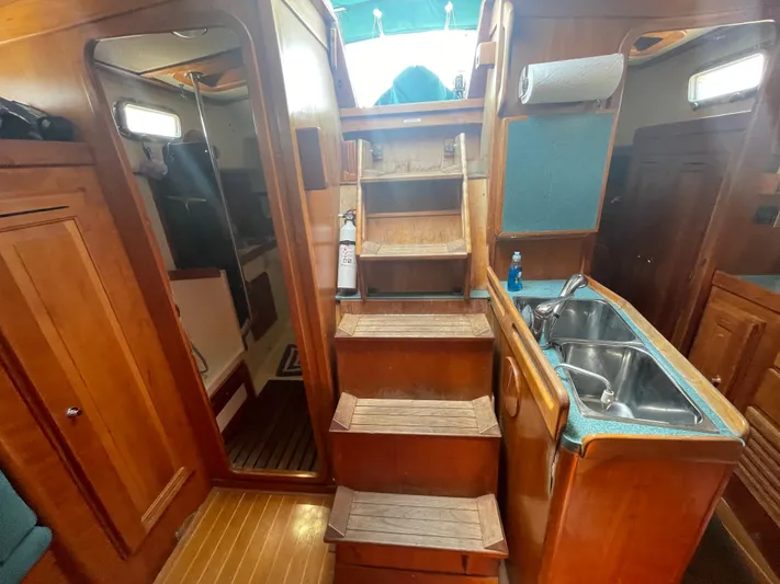  Yacht Photos Pics Interior of 2001 Tartan 4100 sailboat with wooden stairs and compact kitchen area.