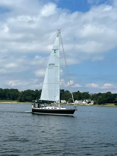  Yacht Photos Pics Sailboat Tartan 4100 (2001) cruising on a calm lake under a partly cloudy sky.