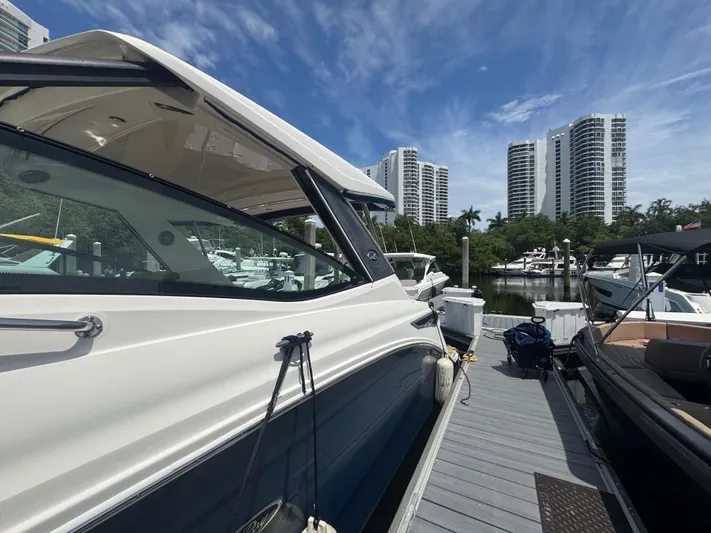  Yacht Photos Pics 2021 Sea Ray Sundancer 320 Coupe Outboard docked with city skyline backdrop.