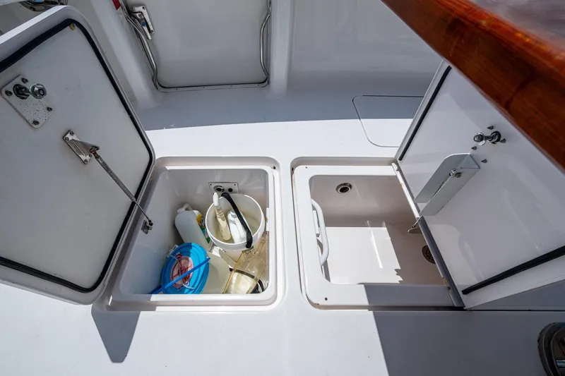 Adrian & Leidiana Yacht Photos Pics Open storage compartments on a 2005 Viking 61 boat deck, containing cleaning supplies.