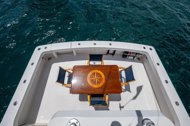 Adrian & Leidiana Yacht Photos Pics 2005 Viking 61 yacht deck with wooden table and chairs, overlooking ocean water.