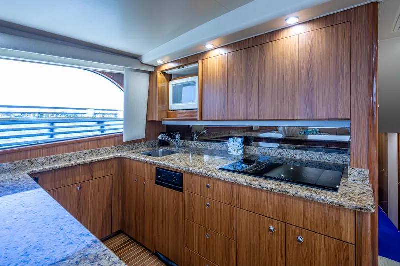 Adrian & Leidiana Yacht Photos Pics Luxurious kitchen interior of 2005 Viking 61 yacht with granite countertops and wooden cabinetry.