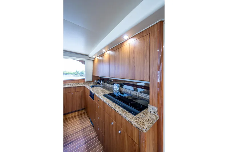 Adrian & Leidiana Yacht Photos Pics Luxurious kitchen interior of 2005 Viking 61 yacht with wood cabinetry and granite countertops.