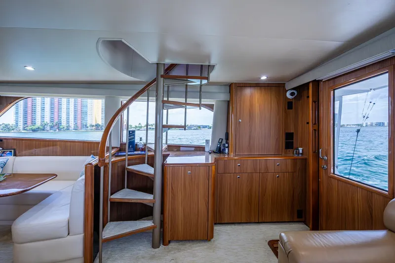 Adrian & Leidiana Yacht Photos Pics Luxurious interior of 2005 Viking 61 yacht with spiral staircase and waterfront view.