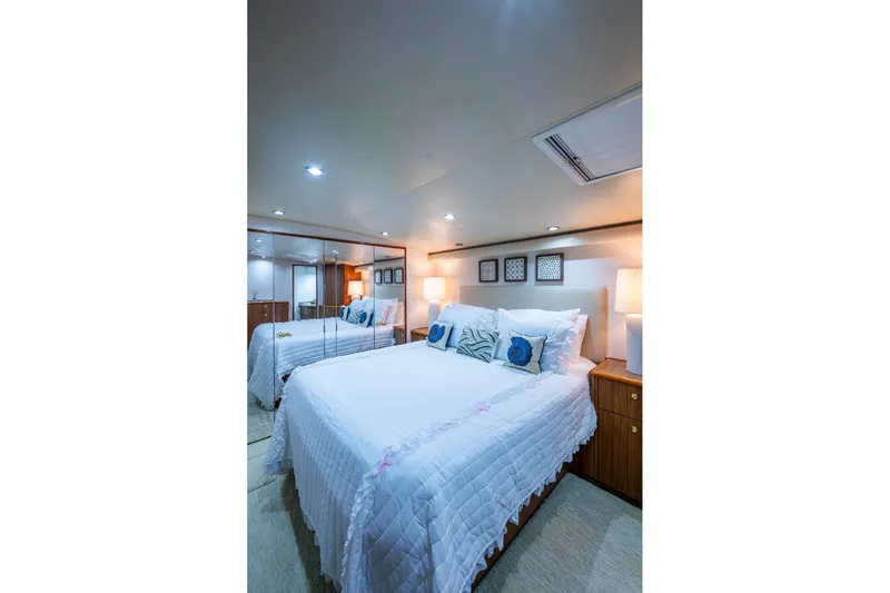 Adrian & Leidiana Yacht Photos Pics Luxurious bedroom interior of 2005 Viking 61 yacht with elegant bedding and ambient lighting.