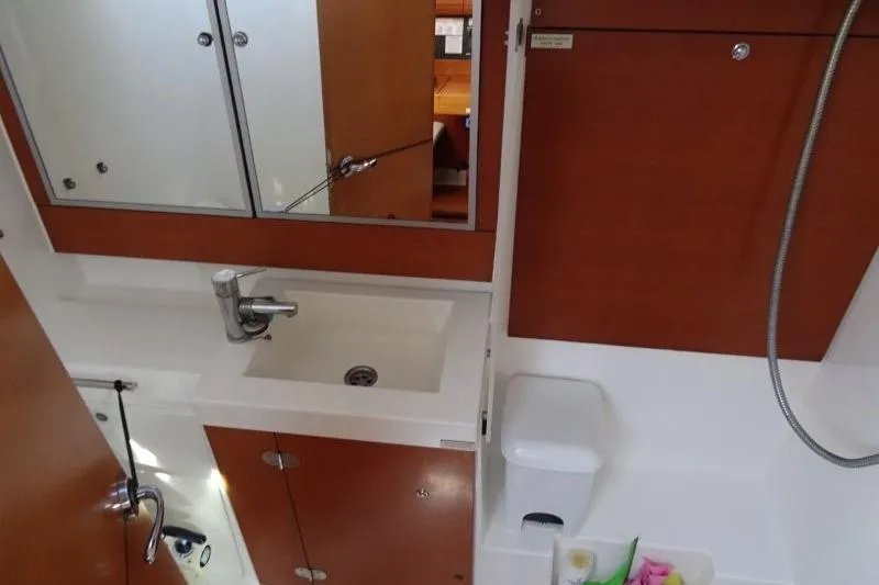 Panopaea Yacht Photos Pics Bathroom interior of 2011 Dufour 405 GL yacht with sink, mirror, and wooden cabinets.