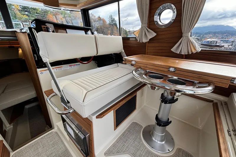  Yacht Photos Pics 2026 Ranger Tugs R-27 interior with white seating, wooden accents, and scenic window view.