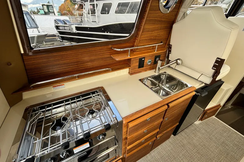  Yacht Photos Pics 2026 Ranger Tugs R-27 interior kitchen with stove, sink, and wooden cabinetry.