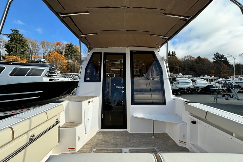  Yacht Photos Pics 2026 Ranger Tugs R-27 boat interior with seating and canopy, docked outdoors.