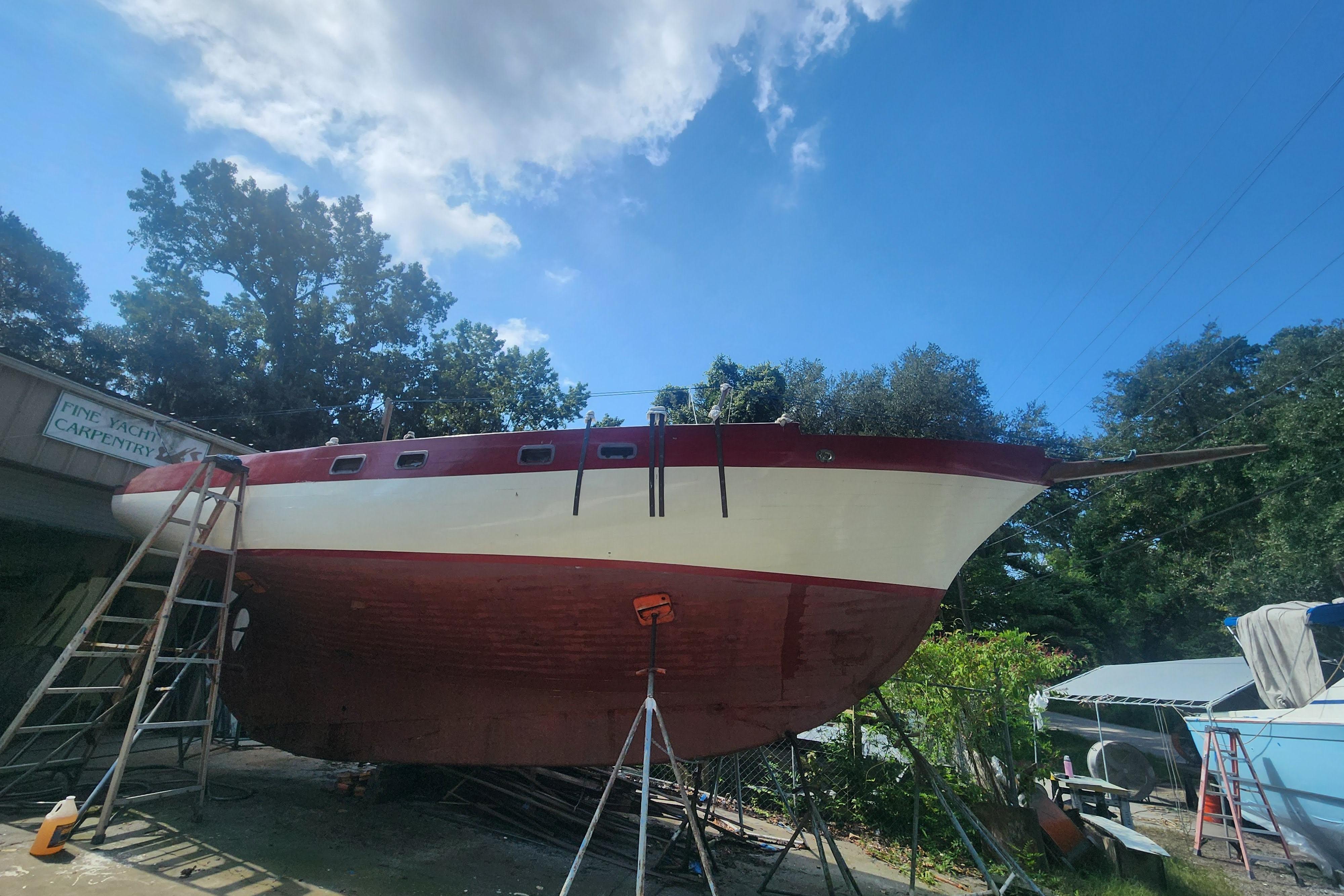 1959 Geerd Hendel Raised-Deck Cutter on dry dock, undergoing maintenance under clear blue sky.