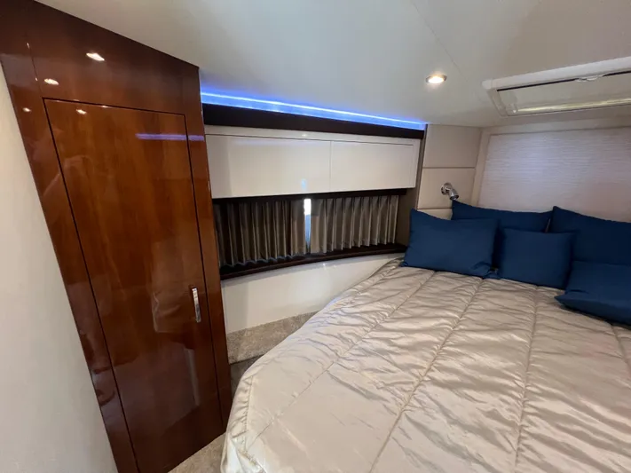 Melody Rose Yacht Photos Pics Interior of 2016 Carver C34 Command Bridge with bed, blue pillows, and wooden cabinetry.