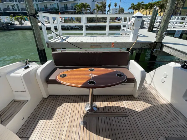 Knot Guilty Yacht Photos Pics Luxury seating area on 2016 Galeon 380 Fly yacht with wooden table and waterfront view.