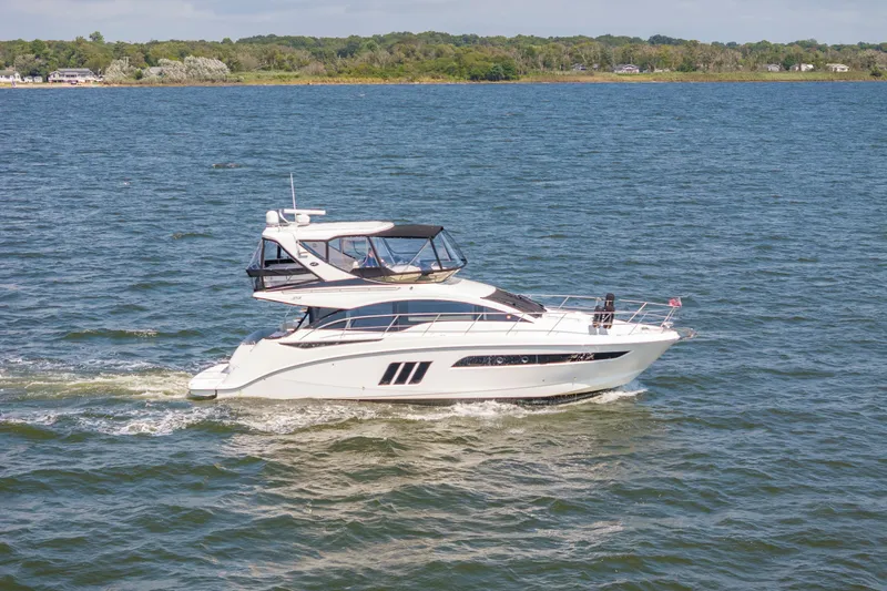  Yacht Photos Pics 2017 Sea Ray Fly 510 yacht cruising on a serene lake with lush green shoreline.