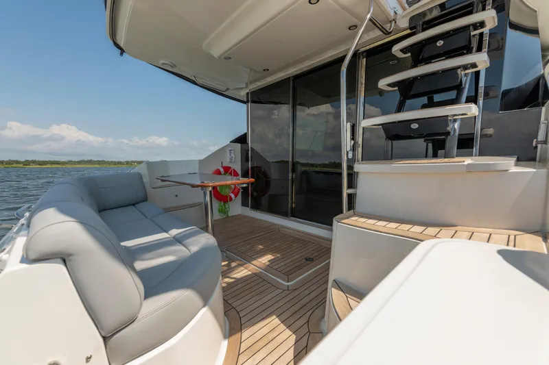  Yacht Photos Pics Luxurious 2017 Sea Ray Fly 510 yacht deck with seating and staircase, overlooking serene waters.