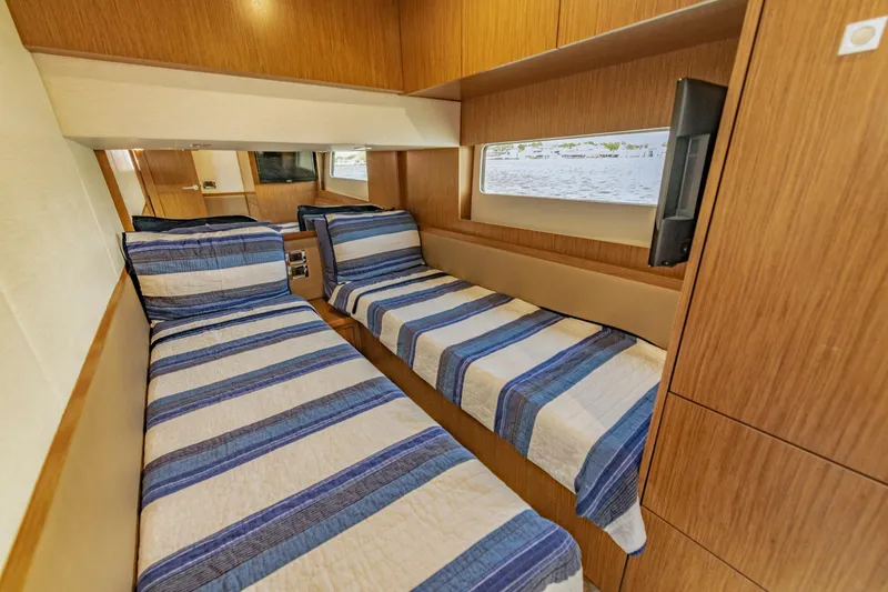  Yacht Photos Pics 2017 Sea Ray Fly 510 cabin with twin beds, striped bedding, and wooden interior.