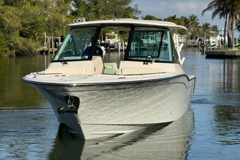  Yacht Photos Pics 2023 Grady-White Freedom 325 boat on calm water, surrounded by lush greenery.
