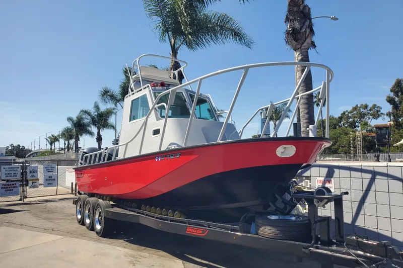  Yacht Photos Pics 1989 Boston Whaler Challenger boat on trailer, red and white, parked near palm trees.