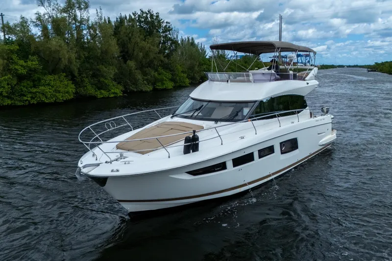  Yacht Photos Pics 2012 Prestige Flybridge yacht cruising on a scenic river under a partly cloudy sky.